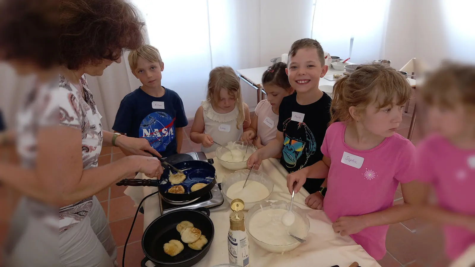 Erika Rahm (Foto, l.) mit einer Kindergruppe beim Backen der Liwanzen. (Bild: Hans Enslein)