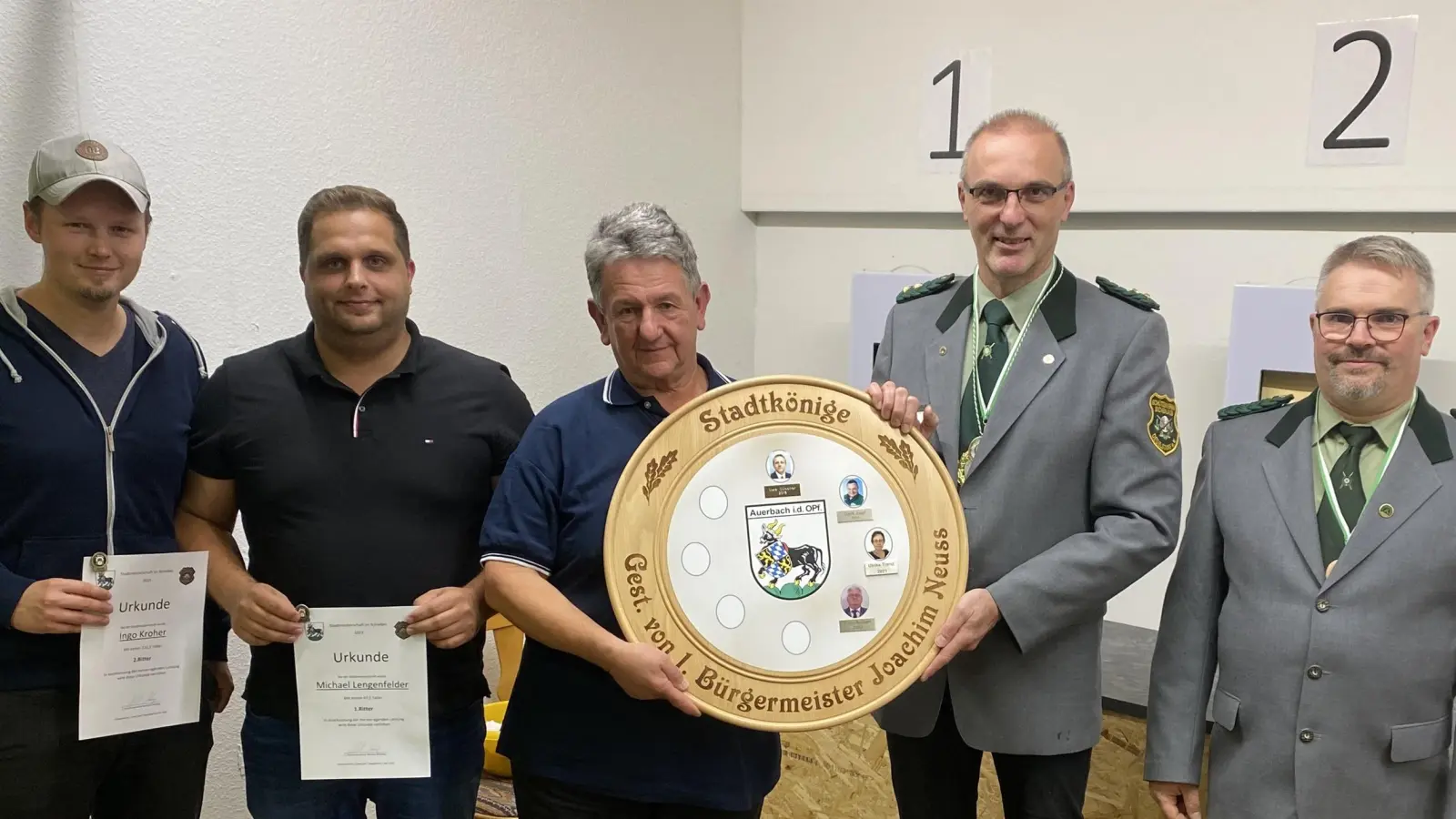 Der neue Schützenkönig in Auerbach, Bernhard Gradl (Mitte), bekommt von Schützenmeister Michael Brütting die Siegerscheibe überreicht. (Bild: jma)