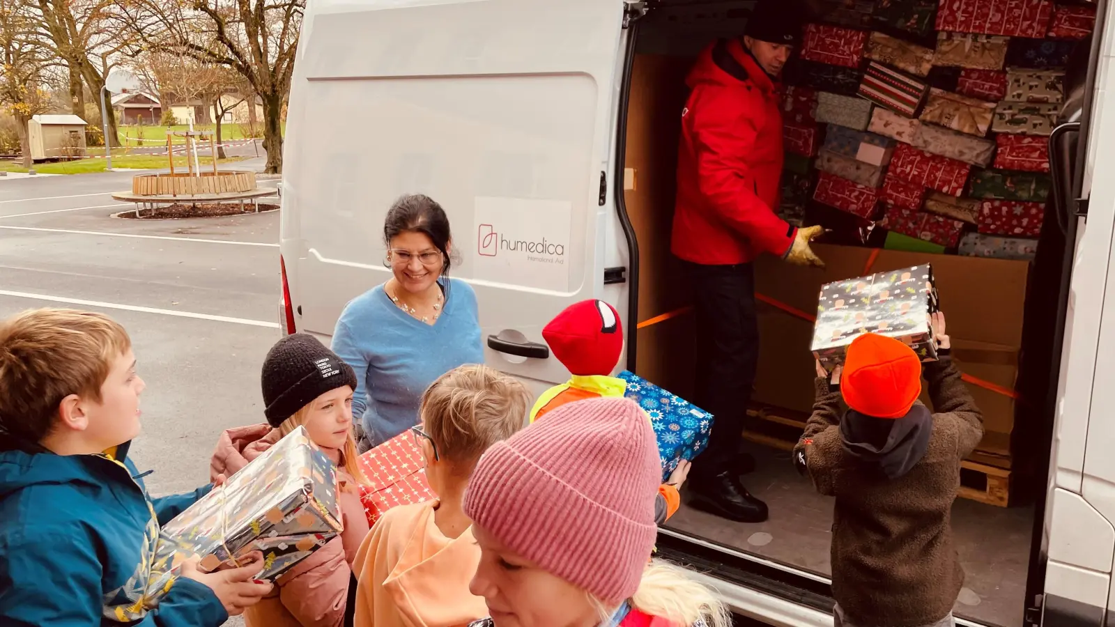 Mehrere Kinder halfen beim Einladen der Weihnachtspäckchen. Mit im Bild Schulleiterin Inge Dick. (Bild: Grundschule Wiesau/exb)