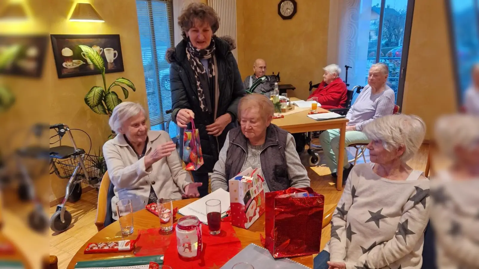 Marga Kraus (stehend) vom VdK-Ortsverband Rieden-Ensdorf-Vilshofen verteilt Weihnachtspackerl an die Bewohner des Ensdorfer Seniorenheims. (Bild: Michael Rabenhofer)