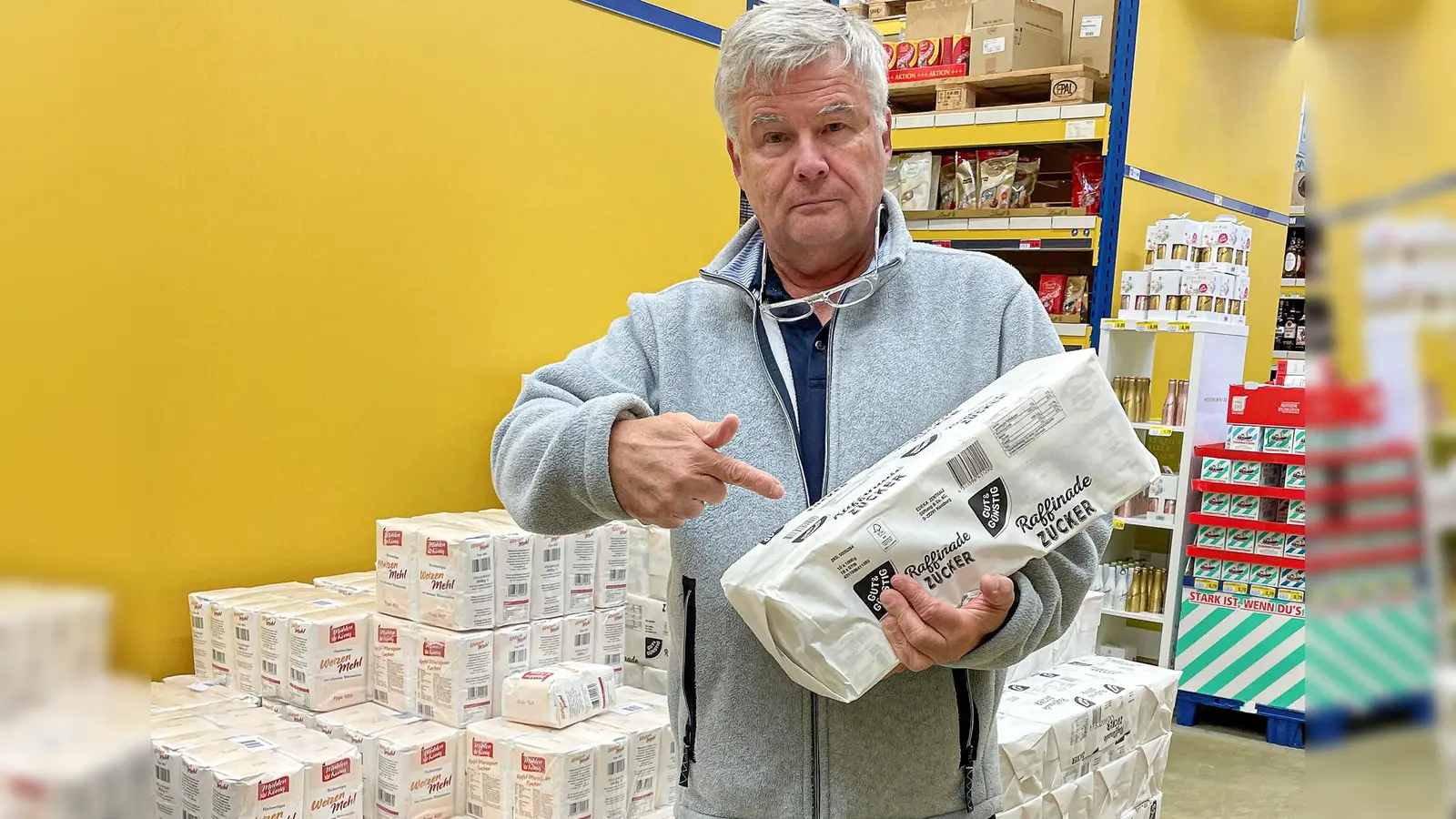 BI-Vorsitzender Michael C. Geiss zeigt, dass Zucker und Mehl, palettenweise eingekauft, für die Tafel mit weniger Organisationsaufwand zu verteilen sind, als bunt gemischte Lebensmittelpakete, die neu sortiert werden müssen. (Bild: MCG-Studios/Michael Geiss)