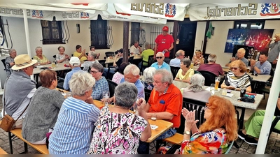 Auf der Terrasse des FC Weiden-Ost feierten heuer die SPD AG 60plus ihr Sommerfest. Vorsitzender Horst Fuchs (stehend) strahlte, als er die rundum besetzten Plätze unter den Sonnenschirmen überblickte. (Bild: Reinhard Kreuzer)