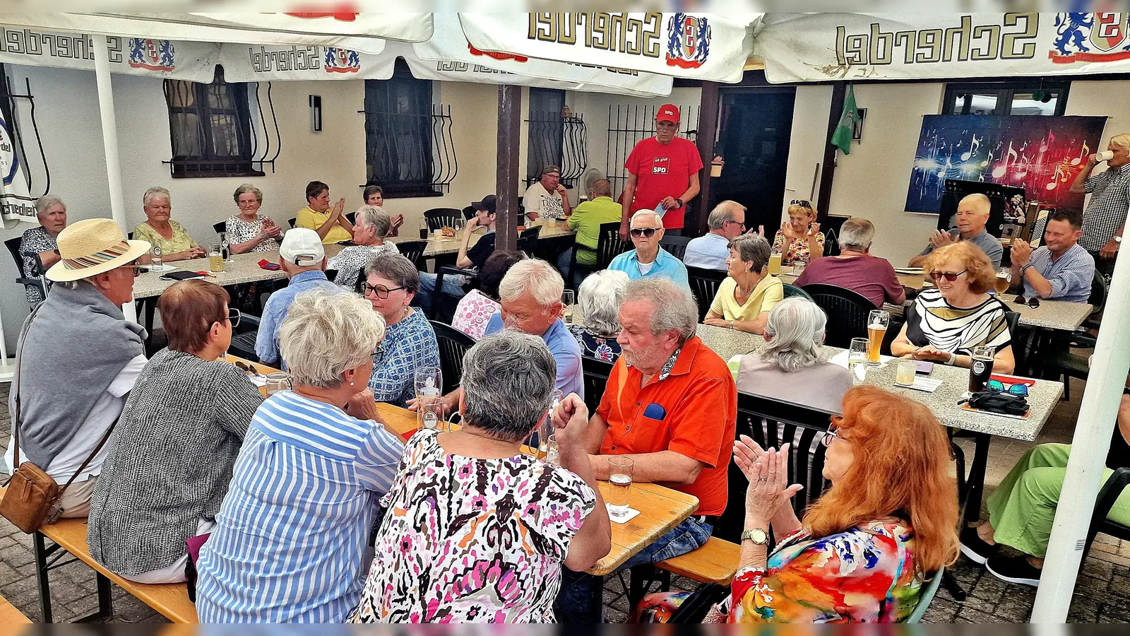 Auf der Terrasse des FC Weiden-Ost feierten heuer die SPD AG 60plus ihr Sommerfest. Vorsitzender Horst Fuchs (stehend) strahlte, als er die rundum besetzten Plätze unter den Sonnenschirmen überblickte. (Bild: Reinhard Kreuzer)
