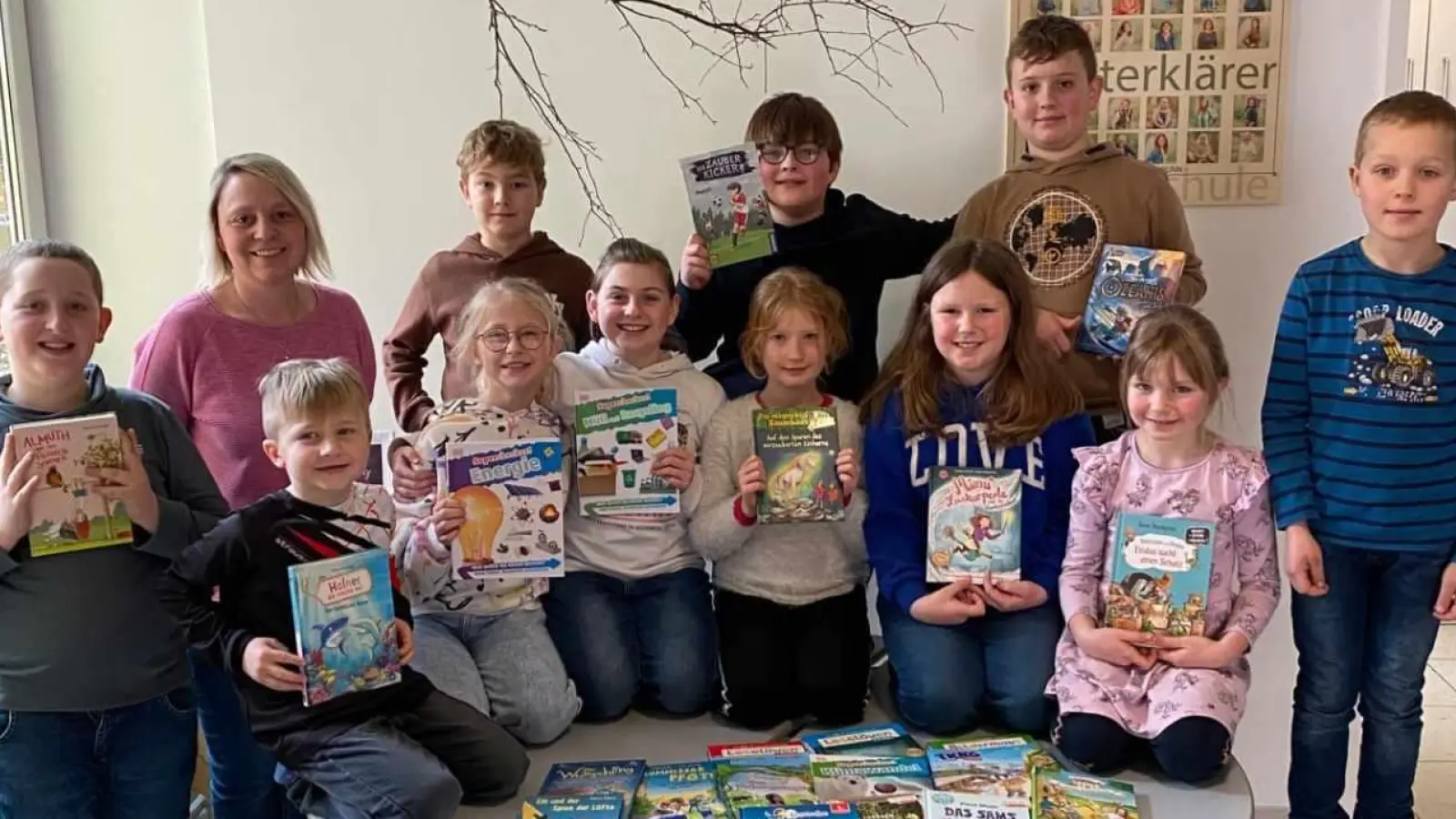 Einige Kinder der Kombiklassen 1/2 und 3/4 und Elternbeiratsmitglied Katrin Koller mit den neuen Büchern für die Schulbücherei.  (Bild: Grundschule Pechbrunn/exb)